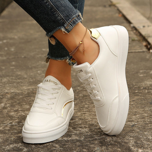 White sneakers worn with rolled-up jeans on a concrete surface