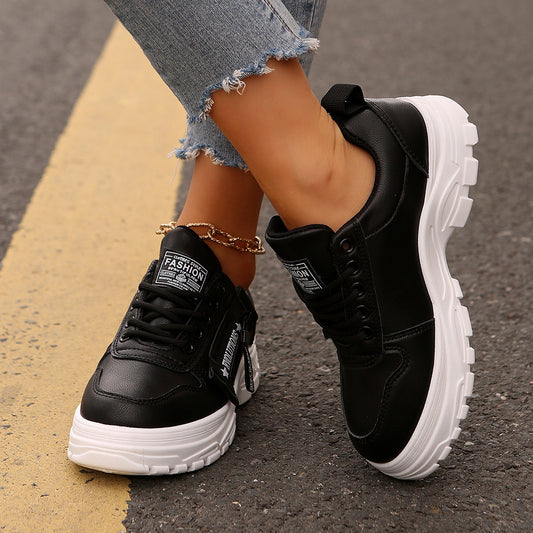 Black sneakers with white soles worn on a street.