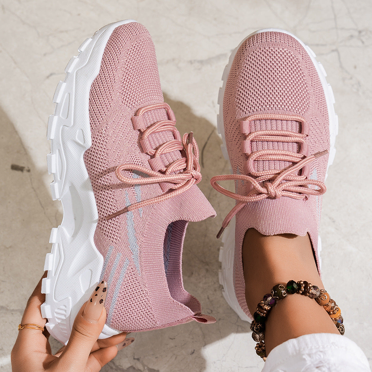 Pink sneakers with white soles held by a person on a light background