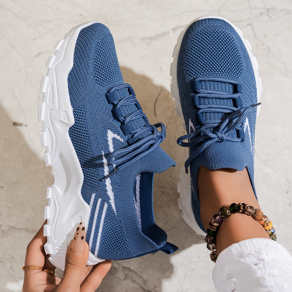 Blue athletic shoes with white soles held by a person on a light background