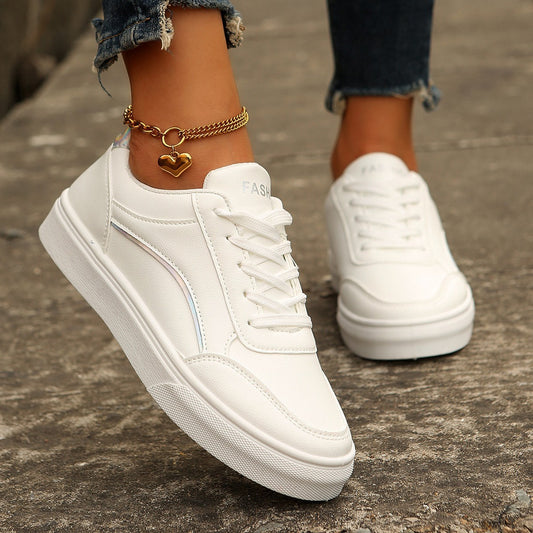 White sneakers worn on a concrete surface with a person's legs and gold anklets visible.
