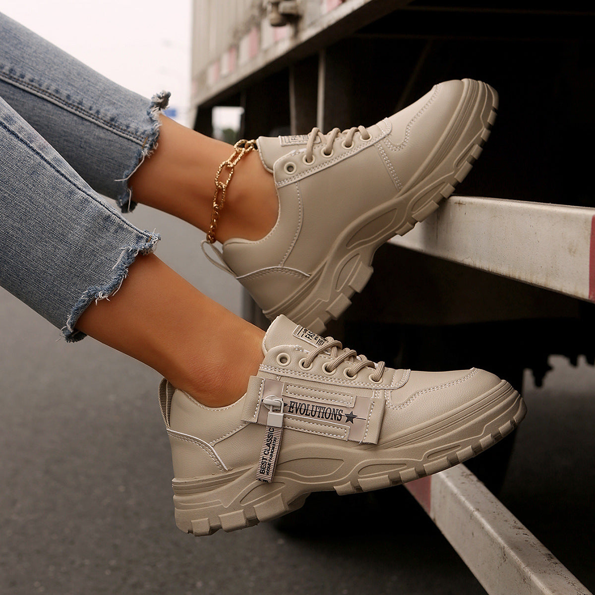 Beige sneakers worn with ripped jeans on a blurred background