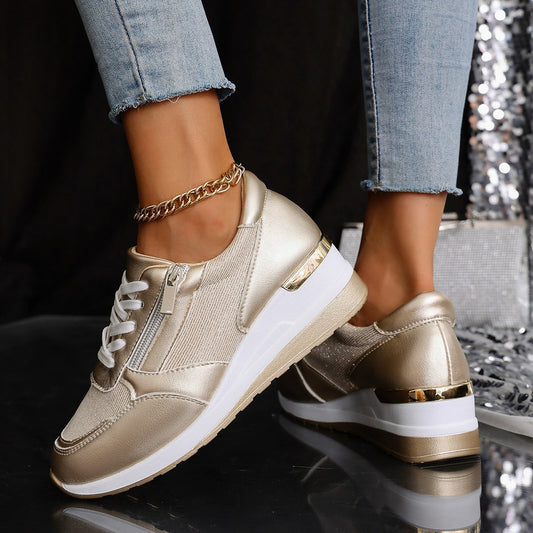 Gold sneakers with white soles worn by a person, on a reflective surface with a dark background.