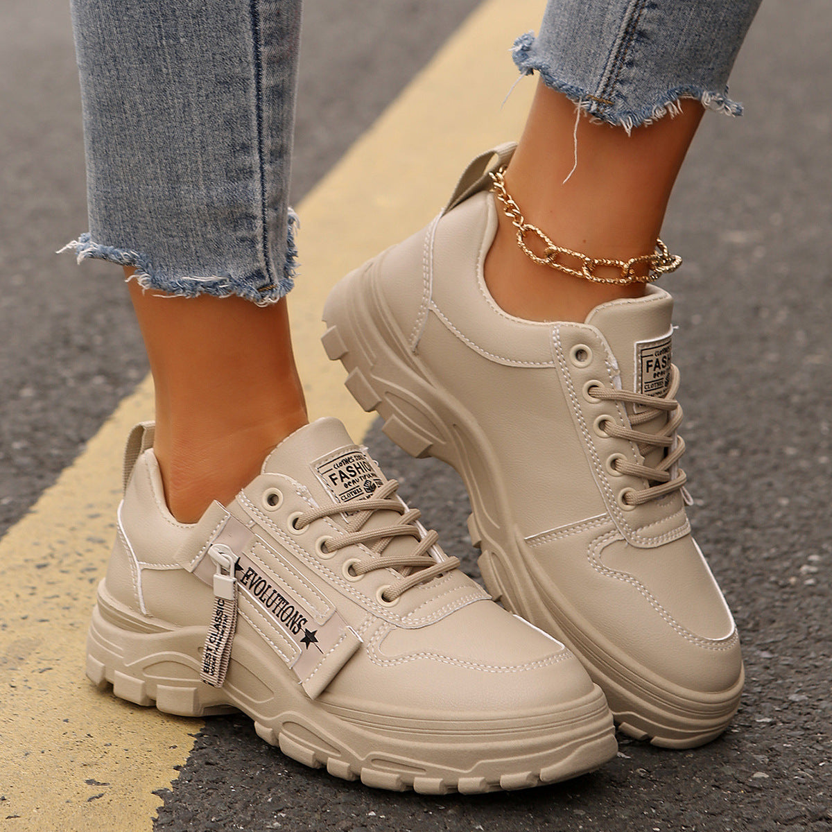 Beige sneakers worn with ripped jeans on a blurred street background