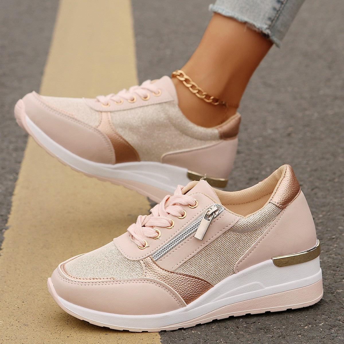 Pink sneakers with gold accents worn by a person on a neutral background