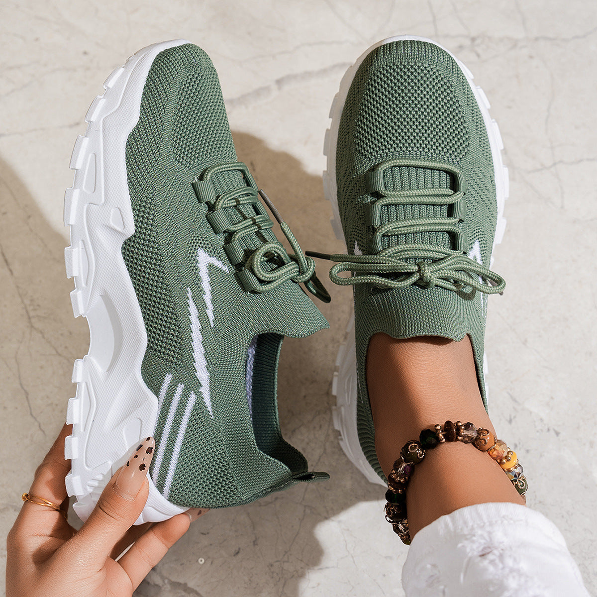 Green running shoes with white soles worn by a person on a light background